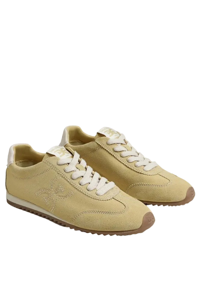 A pair of beige suede sneakers with white laces, a beige heel tab, and a brown gum sole, photographed on a light gray studio background.