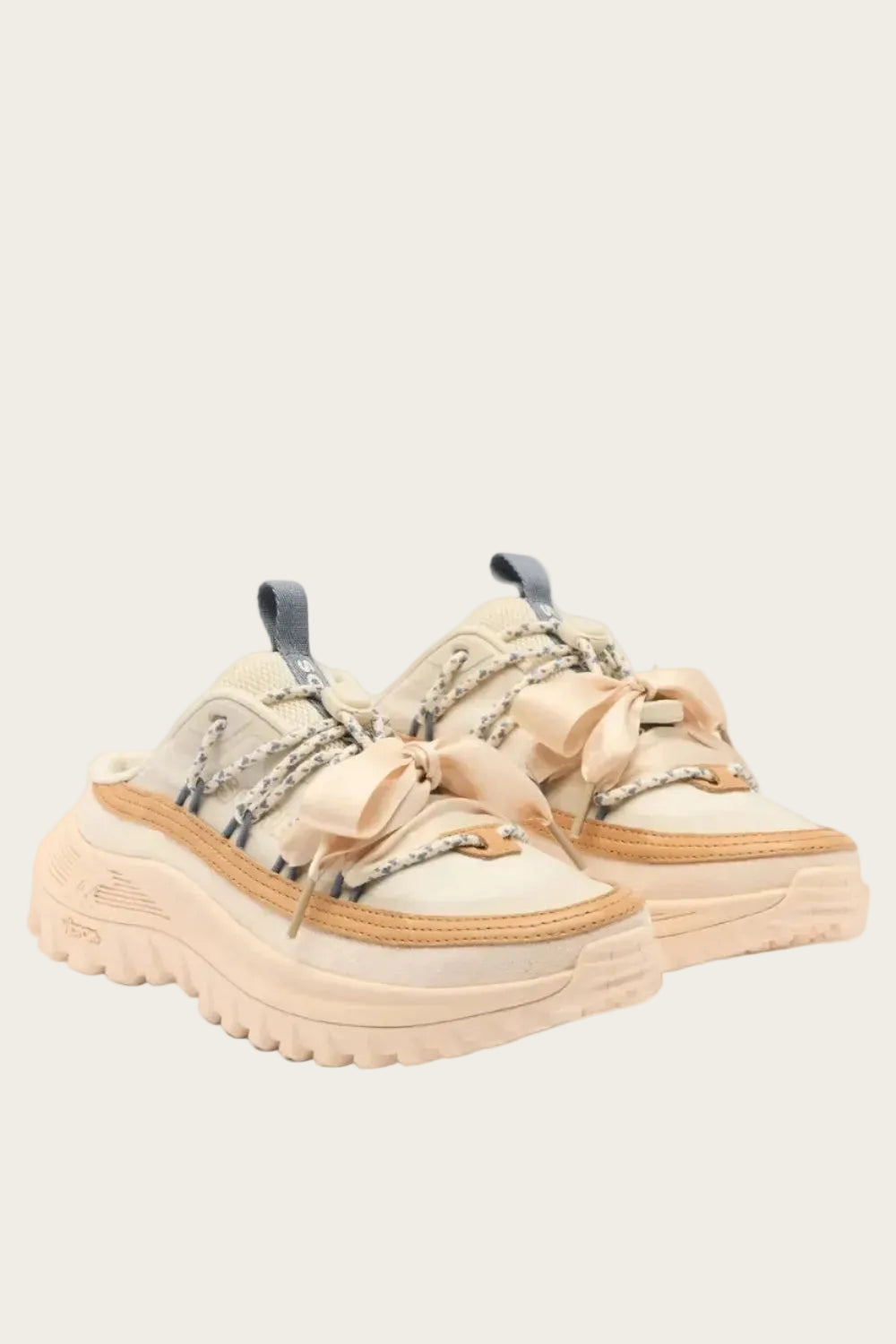 Beige sneakers with decorative bows on a light gray background