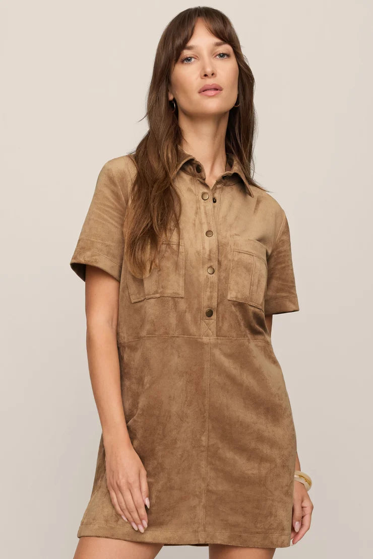Woman wearing a brown suede dress against a plain background