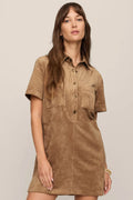 Woman wearing a brown suede dress against a plain background