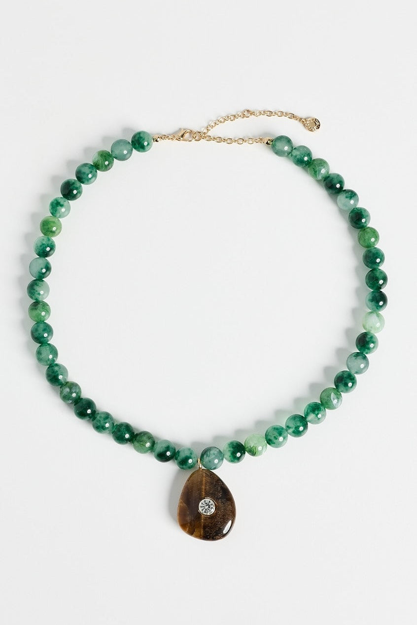 A green beaded necklace with a teardrop-shaped brown stone pendant featuring a small clear stone, displayed on a clean white background.