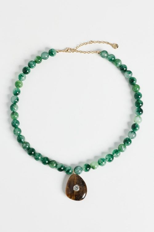 A green beaded necklace with a teardrop-shaped brown stone pendant featuring a small clear stone, displayed on a clean white background.