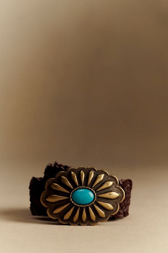 Bracelet with a decorative clasp featuring a turquoise stone on a beige background