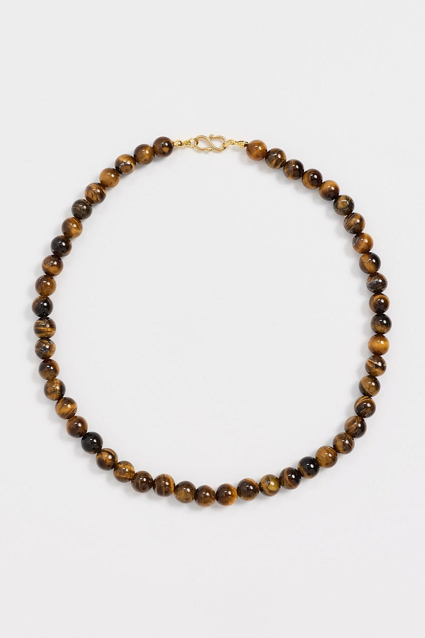A beaded necklace made of round brown and black tiger's eye beads with a small gold clasp, displayed on a clean white background.